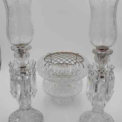 Candelabras and flower frog: The image showcases an arrangement featuring a crystal cut vase with a mesh metal flower frog centerpiece with two candelabras, each adorned with hurricane shades and dangling prisms.