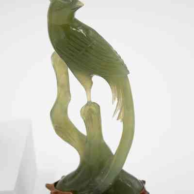 Carved jade bird statuette.: Image of one of the two carved jade bird statuettes on a mahogany wood base.