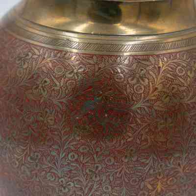 Round urn: A round brass urn features intricate red floral designs etched onto its surface.