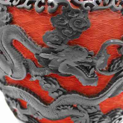 Vase details: The image shows an intricately carved large red cinnabar vase adorned with detailed black dragons in a swirling, dynamic pattern.