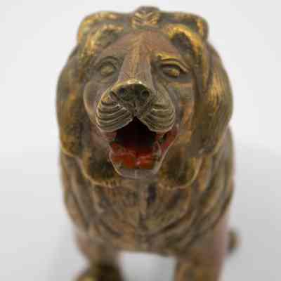 Brass lion face: The lions face has an open, red painted mouth, and thin designs down his skull. His mane has lines indicating hair.