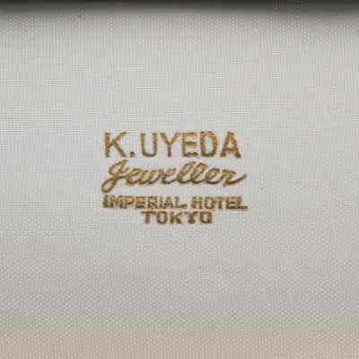 Closeup of label in box: Gold writing in lid of jewelry box, on white fabric it says “K. UYEDA jeweller Imperial Hotel Tokyo.”
