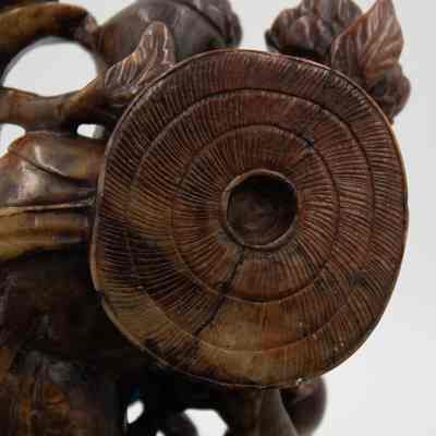 Back of the carved stone woman.: Up close image of the rounded hat on the back of the woman. The piece is marbled brown.