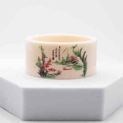 Napkin ring: The image shows an ivory napkin ring, etched with colorful Chinese calligraphy and a serene oriental scene.