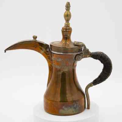 Brass and copper coffee pot: A copper coffee pot with leather-wrapped handle, brass details, and stamped Arabic script.