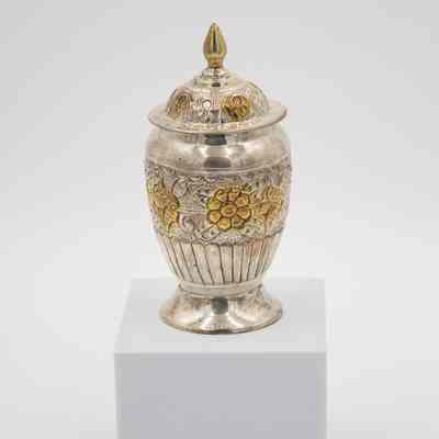 Small urn-shaped sugar jar given to Mrs. Jessie Jordan by Mrs. Al-Ghanim.: Image of the small engraved silver urn-shaped sugar jar decorated with yellow gold roses and a pointed lid.