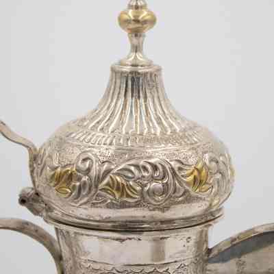 Lid of coffee pot given to Mrs. Jessie Jordan by Mrs. Al-Ghanim.: Up close image of the lid of the engraved silver coffee pot decorated with yellow gold roses.