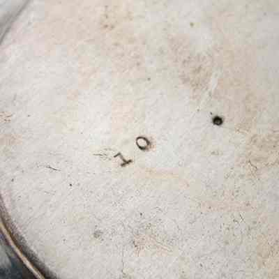 Bottom of coffee pot given to Mrs. Jessie Jordan by Mrs. Al-Ghanim.: Up close image of the bottom of the silver coffee pot engraved with the number "10."