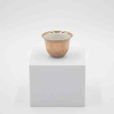 Small teacup given to Mrs. Jessie Jordan by Mrs. Al-Ghanim.: Image of a small porcelain handle-less teacup with gold layer on outside and at the top of the inside rim.