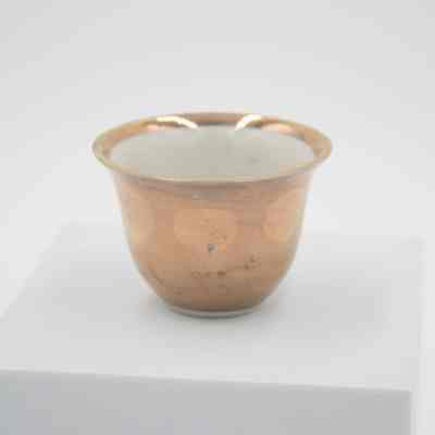 Small teacup given to Mrs. Jessie Jordan by Mrs. Al-Ghanim.: Up close image of the small porcelain handle-less teacup with gold layer on outside and at the top of the inside rim.