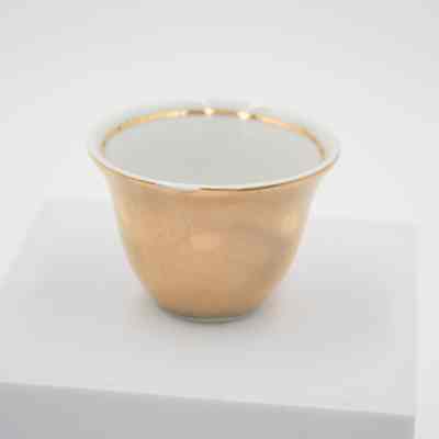 Small teacup given to Mrs. Jessie Jordan by Mrs. Al-Ghanim.: Up close image of the small porcelain handle-less teacup with gold layer on outside and at the top of the inside rim.