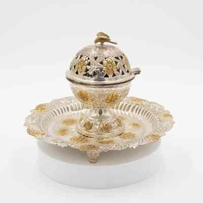 Incense burner and tray given to Mrs. Jessie Jordan by Mrs. Al-Ghanim.: Image of the round engraved silver globe-shaped incense burner on circular tray decorated with yellow gold roses and leaves. There is a gold falcon on top of the incense burner.