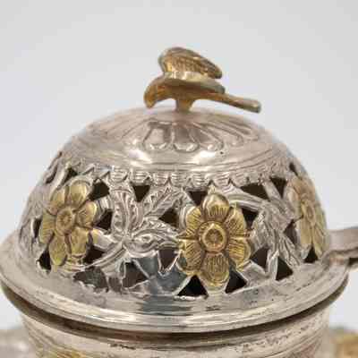 Body of incense burner given to Mrs. Jessie Jordan by Mrs. Al-Ghanim.: Up close image of the body of the globe-shaped incense burner. The incense burner is silver and engraved with leaf and flower details. The flowers are roses and made from yellow gold. There is a gold falcon on top of the lid.
