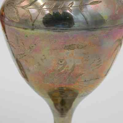 Bird engravings: A scalloped brass vase on a pedestal showcases intricate engraved floral and bird designs.