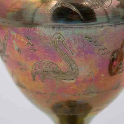 Bird engravings: The image shows a detailed engraving of birds and flowers on a colorful brass vase.