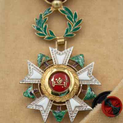 Lebanon National Order of the Cedar Medal: A medal with Arabic script and olive leaf enamel detail, affixed to a red ribbon with a circle pin indicating "Officer Level."