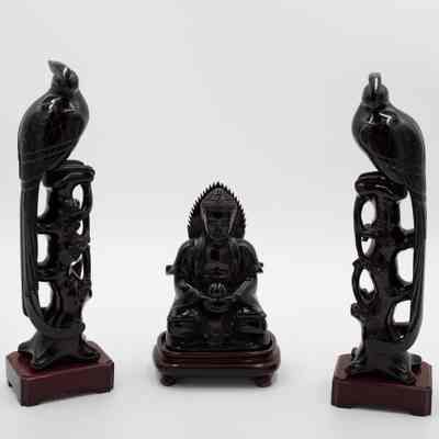 Amber Buddha and birds: The image features two intricately carved red amber bird sculptures, flanking a central statue of Buddha.