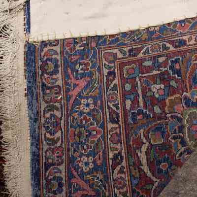 Red and blue area rug: The image shows the backside of a patterned rug with intricate red and blue designs.