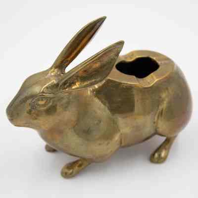Brass rabbit ashtray: A realistic, miniature rabbit ashtray. It is brass with an opening in its back and divots to hold a cigarette. The ashtray is 5 inches long.