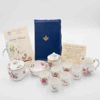 Masonic Presentation Bible and accompanying China.: Image of the blue Masonic presentation Bible and accompanying Royal Crown Derby porcelain: 1 pitcher, 1 jam pot, 1 sugar bowl, 1 small bowl, 6 demitasse cups w/out handles. All of the porcelain is bone China with a floral posies design. There is also the invitation from the event, the "Ladies' Festival," and the program from the event.