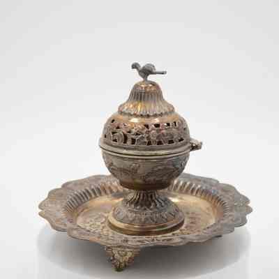 Incense burner and tray given to the Jordans by Sheikh Ahmad Al-Jaber Al-Sabah.: Image of the silver globe-shaped incense burner on circular footed tray. They are both decorated with debossed flowers and vines. There is a small cast bird on the top of the incense burner, it is likely a falcon.