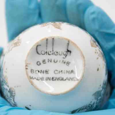 Bottom of small teacup from the coffee service given to the Jordans by Sheikh Ahmad Al-Jaber Al-Sabah.: Up close image of the bottom of the white bone China teacup. The teacup is printed with "Colclough Genuine Bone China, Made in England" on the bottom.