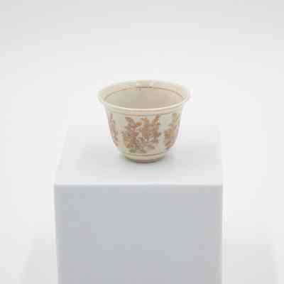 Small cup from the coffee service given to the Jordans by Sheikh Ahmad Al-Jaber Al-Sabah.: Image of a small bone China handle-less teacup decorated with gold foil flowers and leaves. There is a thin gold foil line on the inside rim.
