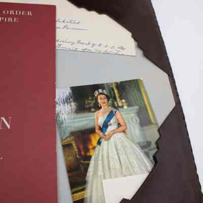 Items inside desk mat: A photograph of Queen Elizabeth II is tucked into one of the corners of the desk mat.