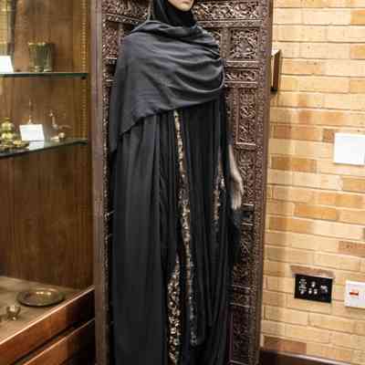 Screens with mannequin: A mannequin in a black outfit stands beside intricately carved wooden screens with a leaf design.
