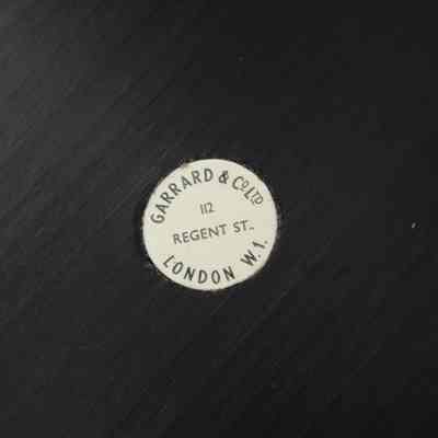Sticker on the bottom of the black base of the silver trophy cup given to Mrs. Jessie Jordan by the Kuwait Gardening Club.: Up close image of a sticker on the bottom of the black base of the silver trophy cup. It denotes the maker as "GARRARD & CO LTD LONDON W.1. 112 REGENT ST."