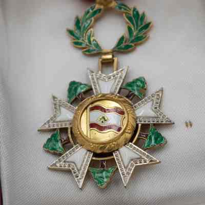 Backside of medal: The image shows the Lebanon National Order of the Cedar Medal, Officer Level, featuring a gold medallion in the center with the Lebanese flag encircled by a laurel wreath.