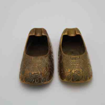 Both shoe ashtrays: The image shows a pair of brass shoe ashtrays featuring a detailed engraved flower design.