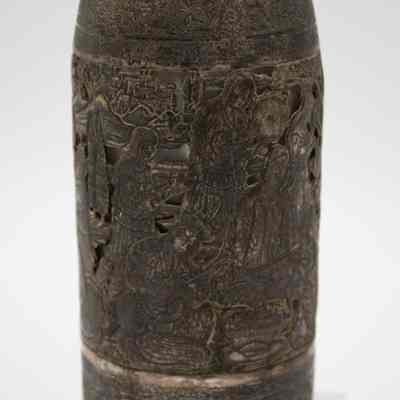 Body of the silver bottle-shaped decanter with chain-attached lid.: Up close image of the silver bottle-shaped decanter with chain-attached lid. The decanter is engraved with scenes of a Persian Banquet of Song and Dance.