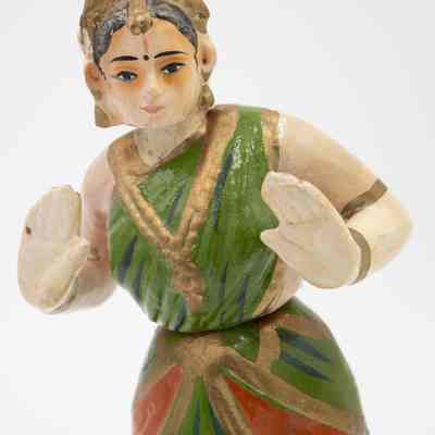 Ceramic Indian dancer: The ceramic Indian dancer figurine is crafted wearing a vibrant green and orange traditional outfit.