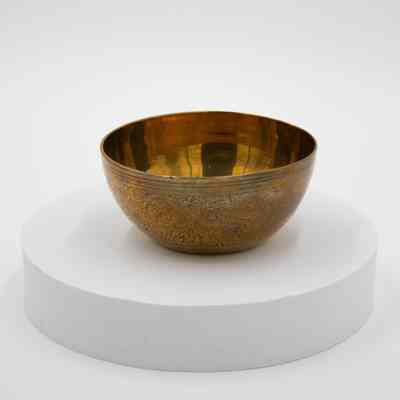 Red bowl: A brass bowl with intricate red floral designs sits elegantly on a white pedestal.