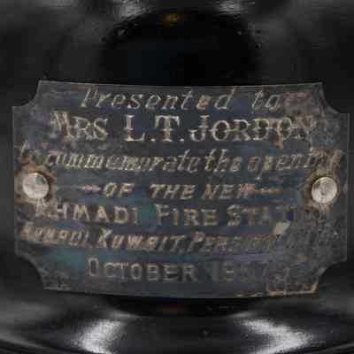 Black Plaque: The black plaque with brass writing states "Presented to MRS L.T. JORDAN to commemorate the opening OF THE NEW AHMADI FIRE STATION Ahmadi, Kuwait, Persian Gulf OCTOBER 1957"