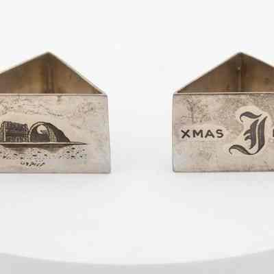 Napkin rings: A pair of triangular metal napkin holders, one engraved with Kuwaiti scenes, and the other with a large J and "XMAS 1951."
