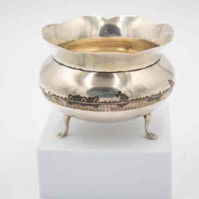 Footed bowl: A silver footed bowl features an intricately etched oasis scene around its polished surface.
