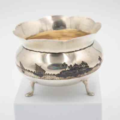 Footed bowl: The silver footed bowl features an etched oasis scene, with intricate details depicted around its rounded exterior, capturing serene landscapes.