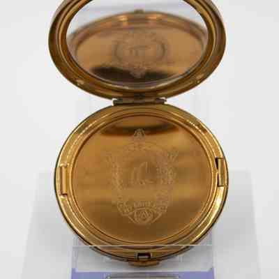 Gold compact from Kuwait Masonic Lodge 6810.: Up close image of the gold compact. There is an engraving of the seal from Kuwait Masonic Lodge 6810. The inside of the lid has a mirror.