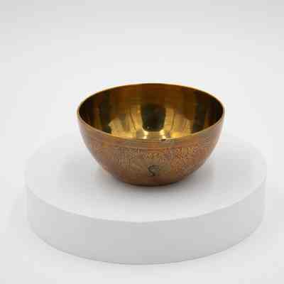 Peacock bowl: A brass bowl is adorned with intricate, red peacock designs.