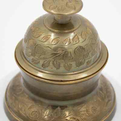 Meditation bell: A beautifully crafted brass meditation bell features intricate leaf designs engraved across its surface.