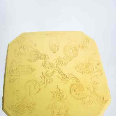 Top of pedestal: An ivory pedestal features carved dragons and faces with intricate details on top.