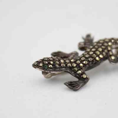 Diamond and emerald lizard brooch that belonged to Mrs. Jessie Jordan.: Up close image of the head of the lizard-shaped brooch with embedded diamonds across the body and two emeralds for eyes.