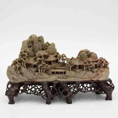 One of two grey stone-carved Shoushan villages.: Image of one of two grey-green stone carved villages on dark brown stands. The villages are Shoushan-style with trees, people, and Chinese houses.