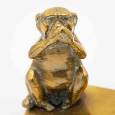 Image of "speak no evil" monkey: Close up image of the "speak no evil" monkey. The brass monkey is holding its hands over its mouth, representing Iwazaru from the original maxim.