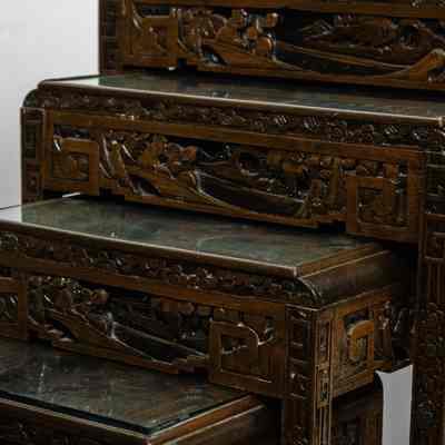Hong Kong nesting tables: The image showcases intricately carved nesting tables from Hong Kong with glass tops, arranged as two sets featuring four rectangular tables each.