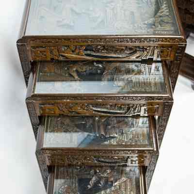Hong Kong nesting tables: The image shows a set of four intricately carved nesting tables from Hong Kong with glass tops, stacked together.
