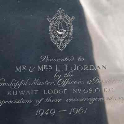 Inscription on plate from Kuwait Masonic Lodge 6810.: Image of the plate engraved with the seal of Kuwait Lodge No. 6810 E.C. and reads “Presented to MR. & MRS. JORDAN by the Worshipful Master, Officers & Brethren of KUWAIT LODGE No. 6810 E.C. in appreciation of their encouragement and support 1949-1961.” The seal of the Kuwait Masonic Lodge has a small Kuwaiti dhow and the traditional Freemason square and compass in it.