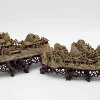 Pair of grey stone-carved Shoushan villages.: Up close image of the set of two grey-green stone carved villages on dark brown stands. The villages are Shoushan-style with trees, people, and Chinese houses.